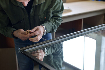 production of cabinet furniture Small-Sized Companies and people concept. young man working at the furniture production. assembly of a mirror door for a sliding wardrobe