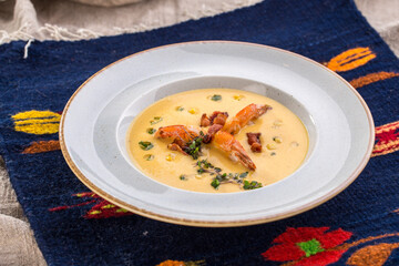 Corn cream soup with shrimp and bacon on the table