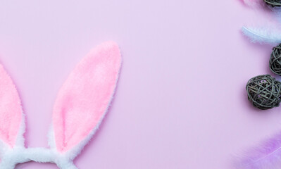 happy Easter.Flatley. Horizontally,on a pink background,close-up with a space for text.Pink rabbit ears,colorful feathers, and brown balls of different sizes that look like eggs.Location at the edges.