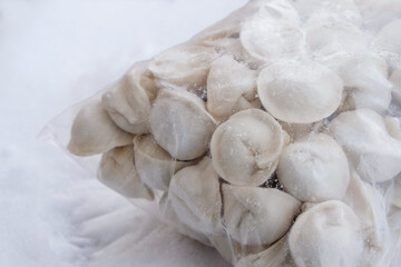 Fototapeta na wymiar Frozen semi-finished products dumplings or pelmeni. Snow surfaces. Sale of finished goods. Frozen food concept. Food delivery and eat at home concept. Copy space. Selective focus.