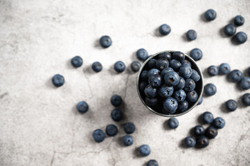 Fresh blueberries in a small metal bucket surrounded with some berries. Top view. Rustic.