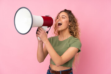 Young blonde woman with curly hair isolated on pink background shouting through a megaphone