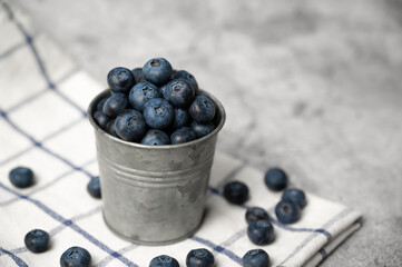 Fresh blueberries in a small metal bucket surrounded with some berries. Side view. Rustic.