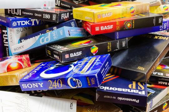 Colorful plastic and paper cases with VHS videotapes.