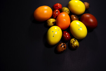 Chicken and quail eggs on a black background. Painted eggs in yellow and brown for the Easter holiday. Eggs with small stars. Front view and copy space