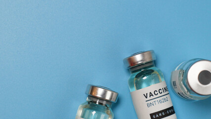 Coronavirus covid-19 experimental vaccine vials on a blue plate with copyspace in a laboratory