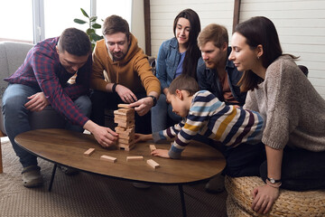 A large group of friends plays board games, a cheerful company at home
