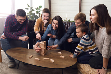 A large group of friends plays board games, a cheerful company at home