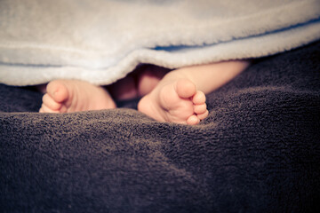 Small, cute baby feet peeking out from a blanket. .