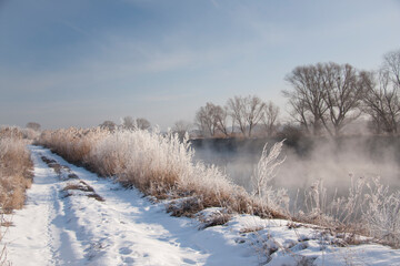 Spring landscape with a river covered with fog, melting snow on the river bank, trees
