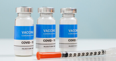 Coronavirus background with vaccine bottle and syringe in the laboratory. Research and development of new cure for diseases