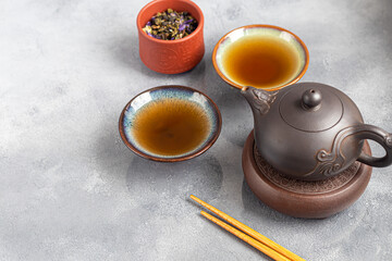 Tea ceremony. Chinese pu-erh in a bowl. In the background is a brown teapot and tea leaves.
