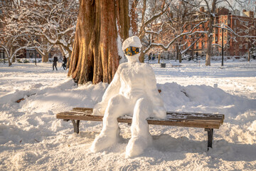 A masked snowman sitting on a bench