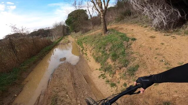 Riding a black mountain bike on a muddy rural road rider point of view