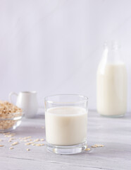 Vegetable oat milk in a glass cup on a light background. Healthy drinks, vegetarianism. Side view. Vertical photo