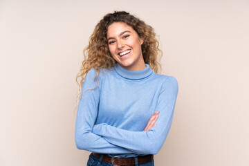 Young blonde woman with curly hair wearing a turtleneck sweater isolated on beige background...