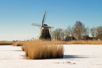 Foto auf Leinwand A landscape of frozen ice with a windmill in the background / Een landschap of  bevroren ijs met op de achtergrond een windmolen © Femke