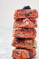Composition with raw square cutlets on light background. Natural food for dogs. BARF dog diet