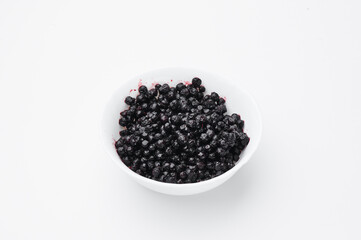 bilberry on a white plate on a white background. Top view. Free space for your text.