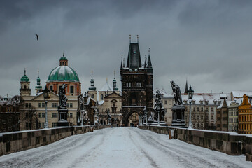 Winter view of Charles bridge, Old Town bridge tower covered with snow, Prague, Czech Republic. People walking through the city in the cold winter morning.Snowy day in town.Popular tourist destination