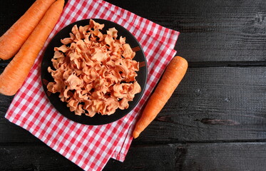 Small homemade carrot chips lie on a black plate on black boards. Rustic. Vegan, Keto, Paleo diet.