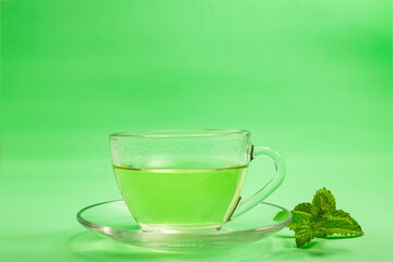 Uma xícara de chá com o fundo verde e um ramo de hortelã.