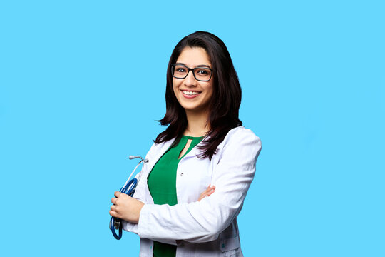 Medical concept of Asian beautiful female doctor in white coat with stethoscope, waist up. Medical student. Woman hospital worker looking at camera and smiling, studio, blue background