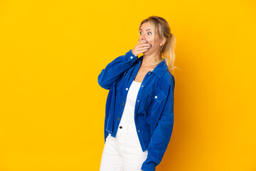 Young Russian woman isolated on yellow background doing surprise gesture while looking to the side