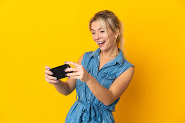 Young Russian woman isolated on yellow background playing with the mobile phone