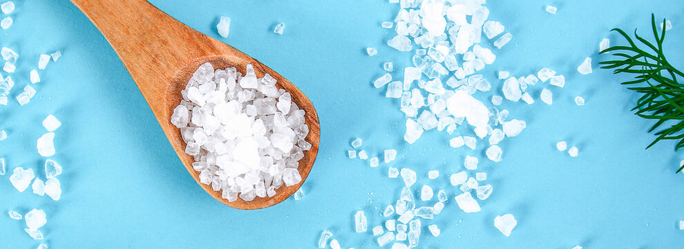 Coarse Salt Crystals On A Blue Table. Wooden Spoon With Sea Salt. Background For Advertising Salty. Banner