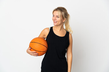Young Russian woman playing basketball isolated on white background looking to the side and smiling