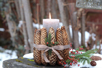 rustikale Winter-Gartendekoration mit Kerze und Tannenzapfen