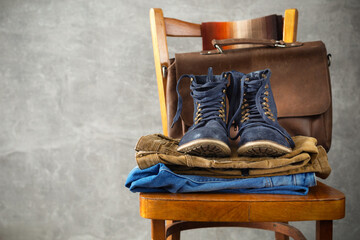 Fototapeta na wymiar Denim jeans and old boots shoes with leather bag at old wooden chair
