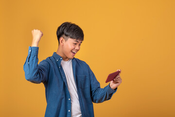 Asian man victory That looks at the phone On orange background