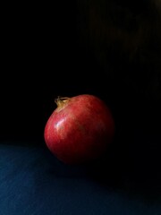 One pomegranate isolated on black background. Low key