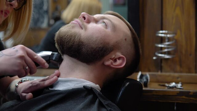 The process of cutting a beard in a barbershop. Close up view from the left side
