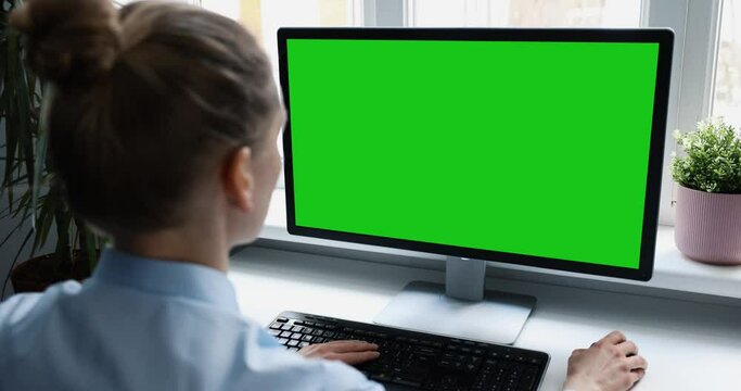 woman using desktop computer in office, scrolling mouse. mockup with blank green screen