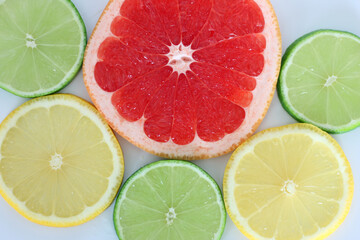 Colorful fruit slices including grapefruit, lemon and lime on a white background.