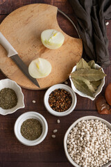 Traditional cuisine - raw beans and seasoning on wooden background