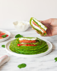 spinach pancakes with salmon, grilled bell pepper, cream cheese, pesto, mascarpone in hand