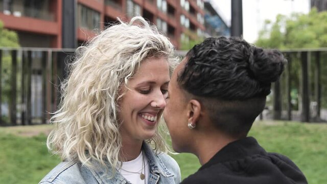 Happy mixed race lesbian couple in love kissing and cuddling - Girlfriends, millennials women, girls in London living happy lifestyle - LGBTQ concept with mixed race beautiful couple
