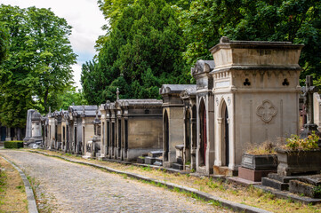 Fototapeta na wymiar Paris, France - July 20, 2019: Narrow alley with tombs at PÃ¨re Lachaise cemetery in Paris, France