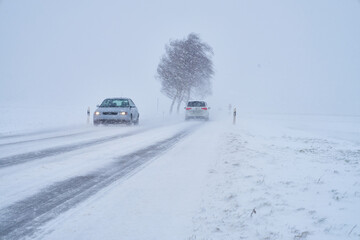 Autos auf Schneebedeckte Landstraße bei Schneesturm im Winter