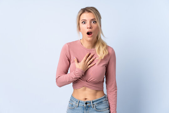 Blonde woman over isolated blue background surprised and shocked while looking right