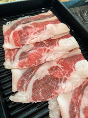 Raw beef thin slice and fresh on black dish.