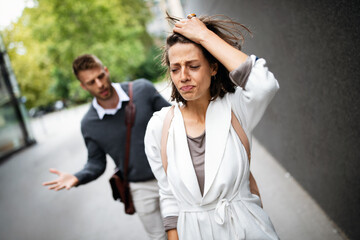 Sad young woman and man outdoor on street having relationship problems