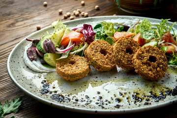 Appetizing salad in the style of oriental cuisine. Fresh vegetable salad with falafel and olive oil served in a blue plate on a wooden background. Restaurant food