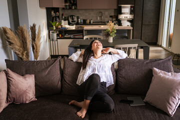 Obraz premium Portrait of a young woman sitting on the couch, smiling and relaxing - Relax concept, thoughtless 