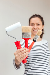 Young woman is painting the wall with paint brushes