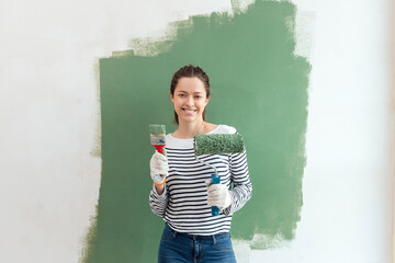 Young woman is painting the wall with paint brushes
